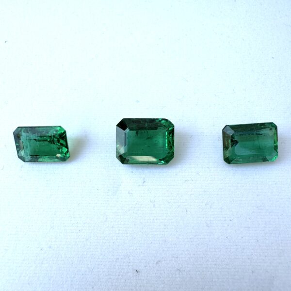 Certified 31-carat emerald-cut Zambian emerald layout of three matched green gemstones.